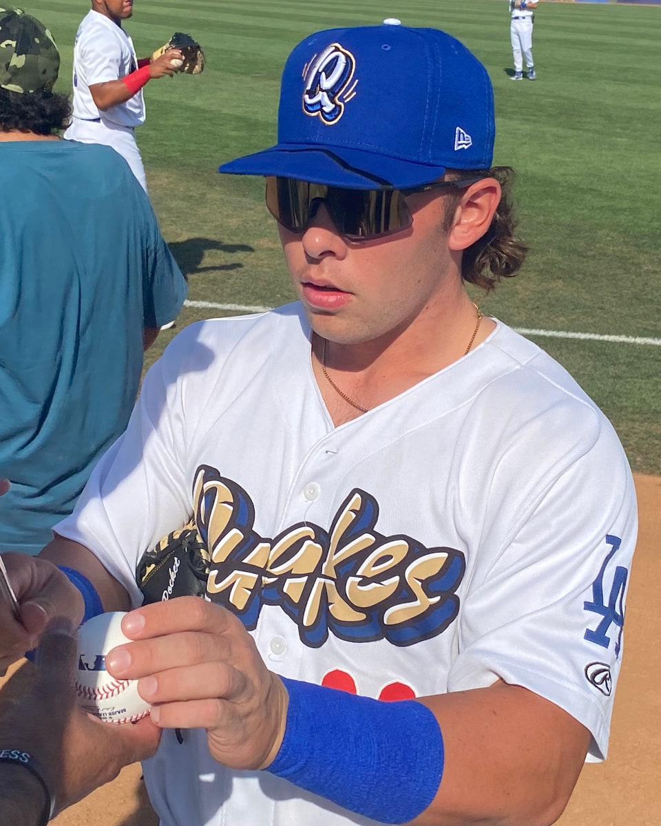 Dalton Rushing signs a baseball in his Rancho Cucamonga Quakes uniform before a 2022 game.